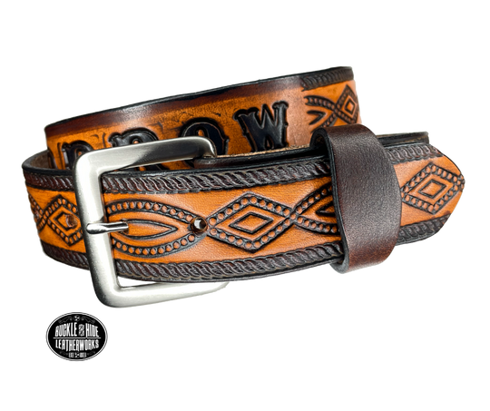 This solid strip of Veg Tan cowhide, is hand stained in classic 2 tone antique brown, with smooth, finished edges. Embossed with a classic FIGURE 8 pattern you'll see "The Stranger" wearing in well known "spaghetti" westerns down length of belt, or have name added to scene up to 8 letters. Belt thickness is approx. 1/8", and 1 1/2" wide. Sizes available are 34" to 44" from buckle end to hole most worn. Attached with 2 snaps is a Brushed Nickel plated solid brass buckle.