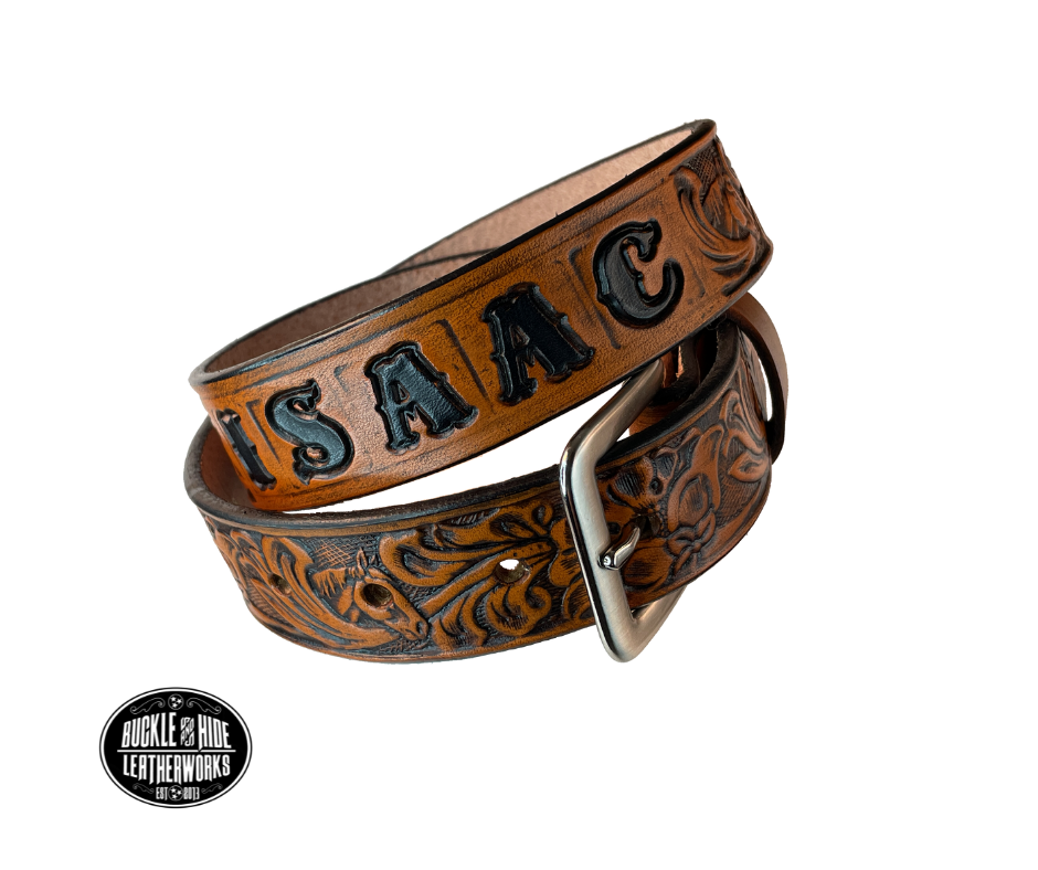Introduce your little one to the iconic style of the west with the "Lil' Mustang" Leather KIDS/CHILDRENS Name Belt! Durable veg tan leather ensures that your cowboy or cowgirl can look good while feeling comfortable, and a unique western floral design featuring horses adds a touch of fun. A 1 1/4" width with snaps makes swapping out buckles a snap! Proudly made in Smyrna TN, just outside Nashville.