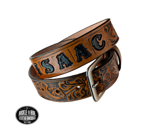 Introduce your little one to the iconic style of the west with the "Lil' Mustang" Leather KIDS/CHILDRENS Name Belt! Durable veg tan leather ensures that your cowboy or cowgirl can look good while feeling comfortable, and a unique western floral design featuring horses adds a touch of fun. A 1 1/4" width with snaps makes swapping out buckles a snap! Proudly made in Smyrna TN, just outside Nashville.
