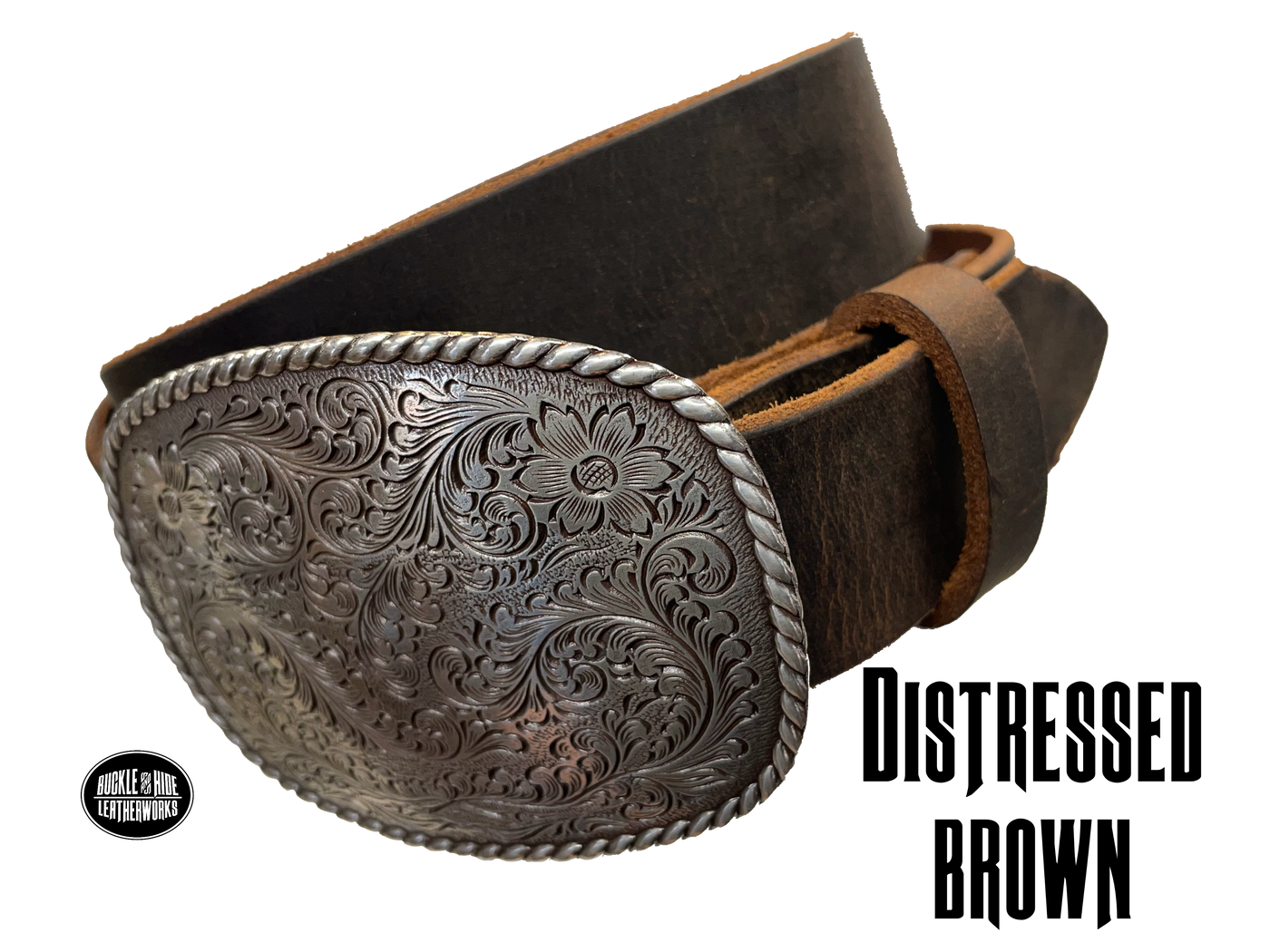 This rectangular shaped buckle by Nocona has rounded edges with rope design around the border. It is chrome colored with scroll design etched appearance on surface.  Measures 2 3/4" tall by 3 3/4" wide and fits belts up to 1 1/2" wide. Buckle is made in Taiwan. Belt is a single strip of leather that is 1 1/2" wide and available in sizes 34" to 44". Colors are distressed brown, black, and dark brown. Distressed brown pictured. Available online and in our retail shop in Smyrna, TN, just outside Nashville.