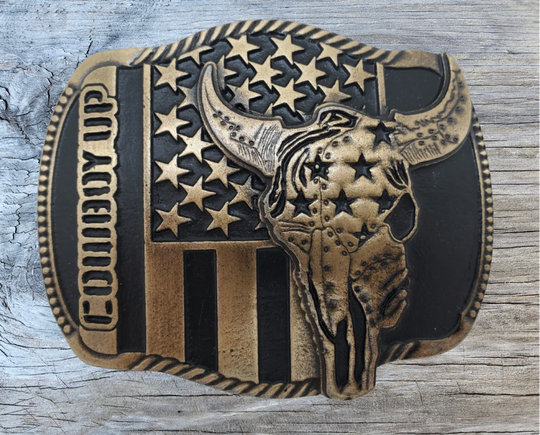 The "Braxton" Belt Buckle is a brass colored oval featuring a Buffalo Skull and a Patriotic USA flag, representing the well-known Rodeo term, "COWBOY UP." It is designed to fit a Standard 1.5 belt and measures approximately 4" x 3". Come visit our shop just outside Nashville in Smyrna, TN to get yours today!