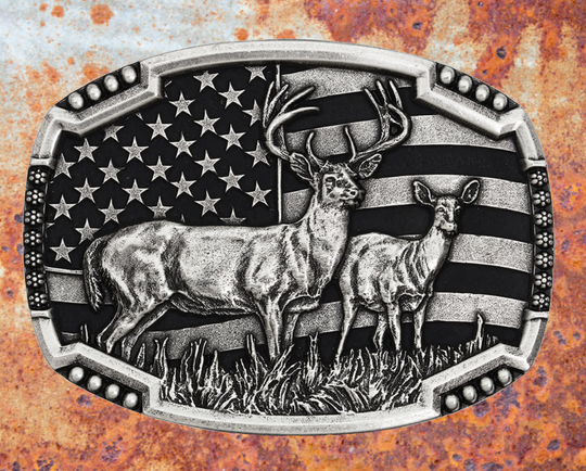 An antiqued silver tone cast buckle with a male and female pair of deer figures standing at attention in the midst of a grassy field. The stars-n-stripes serve as a patriotic backdrop to the animals. The buckle is finished with a smooth wire notched edge with the notches filled with beads. Standard 1.5 inch belt swivel. Available at our shop just outside Nashville in Smyrna, TN. Dimensions: Width 4.00" Height 3.00" Length 0.75"