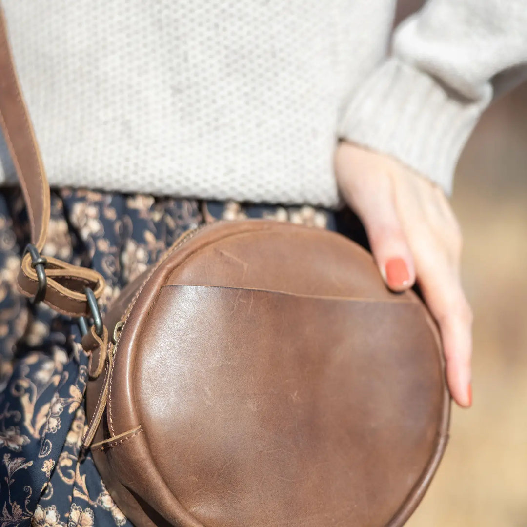 The Greta is a mini round crossbody bag crafted from vegetable-tanned Firenze Antiqua leather. This unlined crossbody features an adjustable strap for perfect fit. The smart key snap attached to the lace ensures effortless access to your essentials, adding a touch of convenience to this elegant accessory. Round everyone up and come see it for yourself at our Smyrna, TN store not far from Murfreesboro.