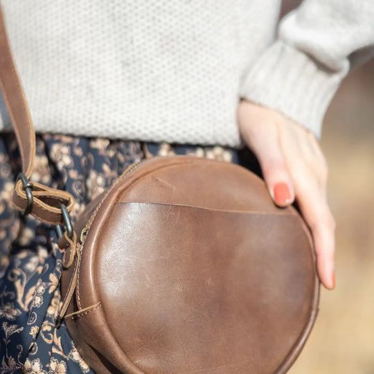 The Greta is a mini round crossbody bag crafted from vegetable-tanned Firenze Antiqua leather. This unlined crossbody features an adjustable strap for perfect fit. The smart key snap attached to the lace ensures effortless access to your essentials, adding a touch of convenience to this elegant accessory. Round everyone up and come see it for yourself at our Smyrna, TN store not far from Murfreesboro.
