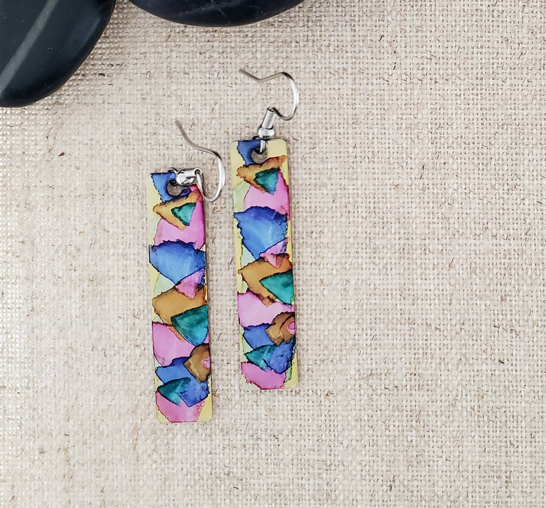 -The stainless steel earring blanks are hand painted with alcohol ink. -They are sealed to keep the finish. -The ear wires are stainless steel. -They measure 2 1/4" in length and 3/8" in width. -Medium weight -THE PHOTO IS AN EXAMPLE OF WHAT YOU WOULD RECEIVE. Each pair is one of a kind. Stocked at our Smyrna, TN shop down I-24 from downtown.