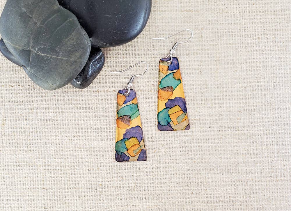 -The earrings are hand cut and finished copper blanks that are then hand painted with alcohol ink. -They are sealed to keep the finish. -The ear wires are stainless steel. -They measure 2" in length and 5/8" in width. -Light weight -THE PHOTO IS AN EXAMPLE OF WHAT YOU WOULD RECEIVE. Each pair is one of a kind. Stocked at our Smyrna, TN shop down I-24 from downtown.