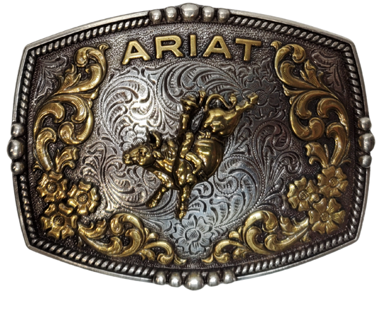 This new Ariat Bull Rider Western Buckle has Bordered with a beaded rope design, is an etched antiqued silver background. In a brass color, Ariat is arched across the top with raised scroll and flower designs surrounding a bull with rider. Measures about 2 3/4" tall by 3 1/2" wide. Fits belts up to 1 3/4" wide. Available for purchase in our online store or the retail shop in Smyrna, TN, just outside Nashville. Imported