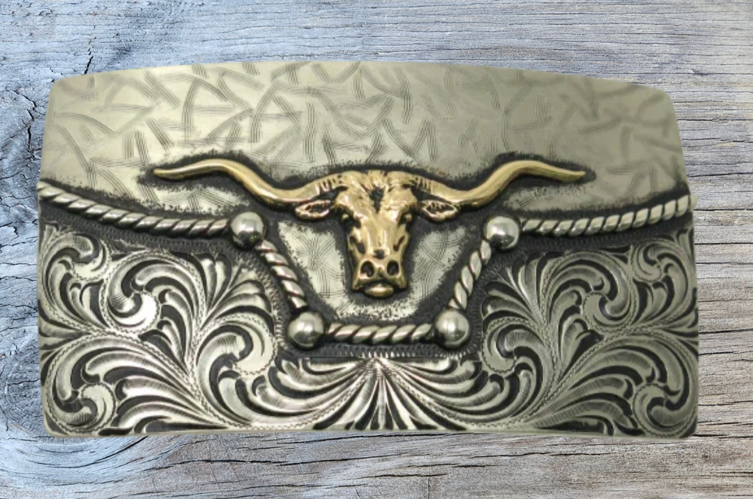 The River Horn impresses with an idea of a longhorn cattle neck deep in a river. In German Silver, the lower half of buckle is engraved in swirls forced from the center. It is separated from the lightly patterned top half with a rope dipping in the center to reveal the brass colored head of a Longhorn cattle. Available in our Smyrna, TN shop, a short distance from Nashville.