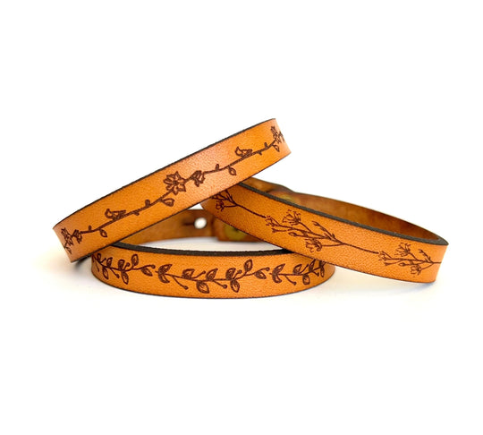 Assorted Floral Laser Engraved Bracelets made from full grain leather. This classic style leather bracelet works great for stacking with each other or any other bracelets. Floral designs are a Daisy Chain, Heather, and Leaves. Closure is a button stud, and adjustable: 7 and 7 1/2 x 3/8 in. Stocked at our Smyrna, TN shop.