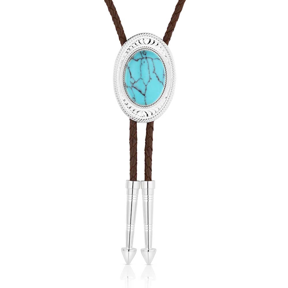 The Outlaw Turquoise Bolo Tie, from Montana Silversmiths is available in our Smyrna, TN shop just outside of Nashville. Has a silver tone oval base that has bright cut engravings that frame the center turquoise stone. The brown braided leather cord is weighed with two silver arrow pointed tips to complete the bold design. Stone color and detail will vary.