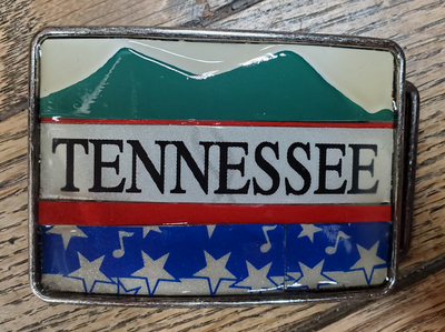 Hand Crafted Tennessee mountains look with our handmade license plate belt buckle. It's a great choice for cheering on your favorite Tennessee teams or for celebrating the great volunteer state! This eye-catching piece measures approx. 3" x 4" and can be matched with any 1 1/2" belt. Get yours today from our Smyrna, TN (near Nashville) store or online and show your style!