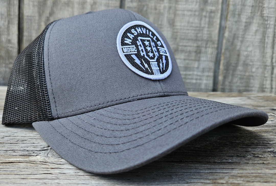 Classic Patched Cap with Music City Nashville and shape of guitar head in the center. Patch is front and center of a snapback cap. This will soon become your favorite cap! Shop now at our Smyrna, TN store or online.

snap back adjustment
Charcoal front with black mesh back