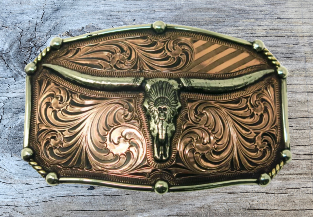 The Chief Longhorn buckle  These buckles are made from German Silver (nickel and brass alloy) or iron metal base. Some buckles have motifs made of copper, iron or brass and some are adorned with synthetic stones. These are all handcrafted. Each piece is punched, cut, soldered, engraved, polished and painted by our talented metal workers.  Available in our Smyrna TN shop. Width 4.5” Height 3”
Fits Standard 1.5” belts