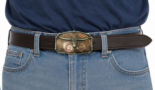 The Chief Longhorn buckle  These buckles are made from German Silver (nickel and brass alloy) or iron metal base. Some buckles have motifs made of copper, iron or brass and some are adorned with synthetic stones. These are all handcrafted. Each piece is punched, cut, soldered, engraved, polished and painted by our talented metal workers.  Available in our Smyrna TN shop. Width 4.5” Height 3”
Fits Standard 1.5” belts