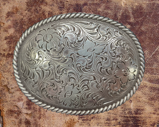 This oval shaped buckle by Nocona has a rope design around the border. It is chrome colored with scroll design etched appearance on surface.  Measures 2 3/4" tall by 3 3/4" wide and fits belts up to 1 1/2" wide.  It is available for purchase in our retail shop in Smyrna, TN, just outside Nashville and also on our online store. Made in Taiwan. Back of buckle pictured.