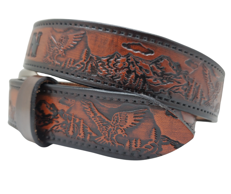 Get ready for an unforgettable climb to the top with The "Eagle Mountain" Name Belt! This one-of-a-kind belt features a 1 1/2" width and is hand-stained with a strip of vegetable tanned leather. The bold design includes a embossed Stitch border and Eagle center pattern, while the solid brass buckle in antique nickel finish adds a touch of ruggedness. Handcrafted at our shop in Smyrna, Tennessee, just outside Nashville.