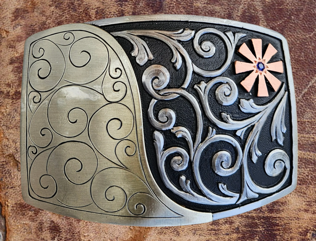 The Endless Breeze Belt Buckle has a more contemporary design accented with multi Scrolls divided into right and left colors and a Copper colored cog wheel on the top right. Made from German Silver and engraved and layered metals in a tri-color design. Available in our Smyrna, TN shop, a short distance from Nashville.

Dimensions: Width 4”, Height 2.7”
Standard 1.5” Swivel
