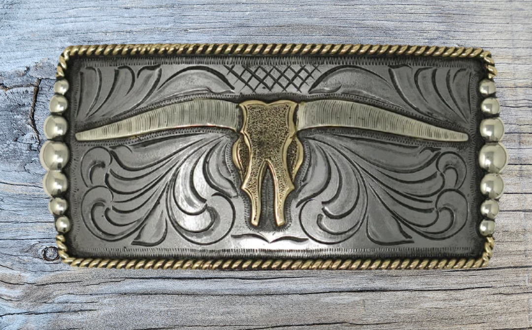 One of our more unique buckles, it has a rectangle shape with a Western scroll design, and a beaded rope edge framing a Longhorn steer. This buckle is made from German Silver (nickel and brass alloy) or iron metal base. Some buckles have motifs made of copper, iron or brass and some are adorned with synthetic stones. Buckle size is Width 5” Height 2” and is available in our Smyrna, TN shop.