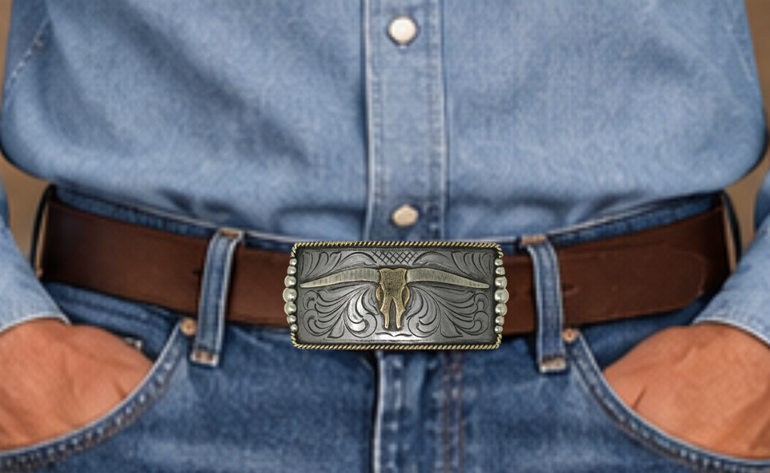 One of our more unique buckles, it has a rectangle shape with a Western scroll design, and a beaded rope edge framing a Longhorn steer. This buckle is made from German Silver (nickel and brass alloy) or iron metal base. Some buckles have motifs made of copper, iron or brass and some are adorned with synthetic stones. Buckle size is Width 5” Height 2” and is available in our Smyrna, TN shop.