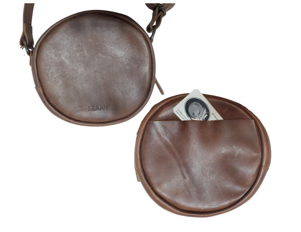 The Greta is a mini round crossbody bag crafted from vegetable-tanned Firenze Antiqua leather. This unlined crossbody features an adjustable strap for perfect fit. The smart key snap attached to the lace ensures effortless access to your essentials, adding a touch of convenience to this elegant accessory. Round everyone up and come see it for yourself at our Smyrna, TN store not far from Murfreesboro.