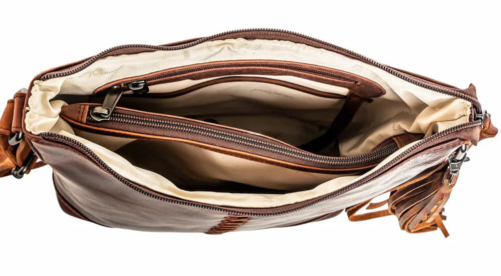 The Blake Scooped Leather Crossbody is crafted from premium full-grain leather, each piece showcasing its own natural variations in grain and shading. Intricate leather crisscross stitching adorns the front and sides, complemented by decorative long tassels for added charm. A large open pocket for your cell phone, and a leather key strap. A zippered pocket on the back adds more room for your essentials. Part of our Carry Conceal Handbags in our Smyrna, TN shop.