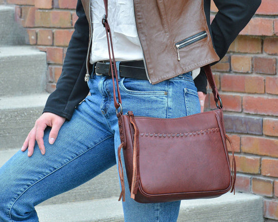 The Callie Leather Crossbody is crafted with quality full-grain leather, featuring stylish lacing on the front pocket and ends. The interior features a zippered pocket, 2 open slip pockets, another large open pocket, and a key strap for fast access to your keys. An additional zippered pocket on the back adds more room for your cell phone or other essentials. The ideal size for the lady on the go. Part of our Cary Conceal Handbags at our Smyrna, TN shop.