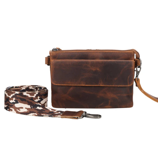 The Natasha Crossbody purse is available at our Smyrna, TN shop. Features full-grain leather front flap pocket, RFID-protected, includes an organizer with 4 credit card slots and a magnetic snap closure. Behind it is an open pocket with a magnetic snap closure, ideal for your cell phone. The main interior is divided into 2 parts and features a zippered pocket, an open slip pocket, and a leather key strap. The bag comes with two crossbody straps: one leather strap and a nylon camouflage strap.