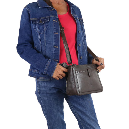 The Leah Crossbody is crafted with buffalo leather and has a light sprinkling of gunmetal studs. The front pocket is secured with a snap closure, contains a slim wallet. This RFID-protected wallet features 2 ID holders, 10 credit card slots, 2 open slit pockets for bills, and a full-size zippered pocket, ensuring your essentials are both organized and secure. The main interior is divided into two sections by a full-length zippered pocket. The front compartment offers two open slip pockets, while the back po