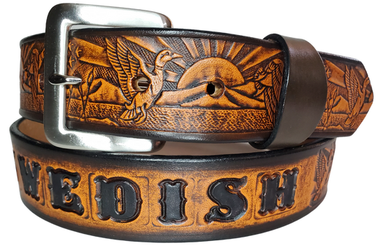 This solid strip of Veg Tan cowhide, is hand stained in 4 brown options, with smooth, finished edges. Embossed with a Mallard Duck scene down length of belt, or have name added to scene up to 8 letters. Belt thickness is approx. 1/8", and 1 1/2" wide. Sizes available are 34" to 44" from buckle end to hole most worn. Attached with 2 snaps is a Brushed Nickel plated solid brass buckle. 