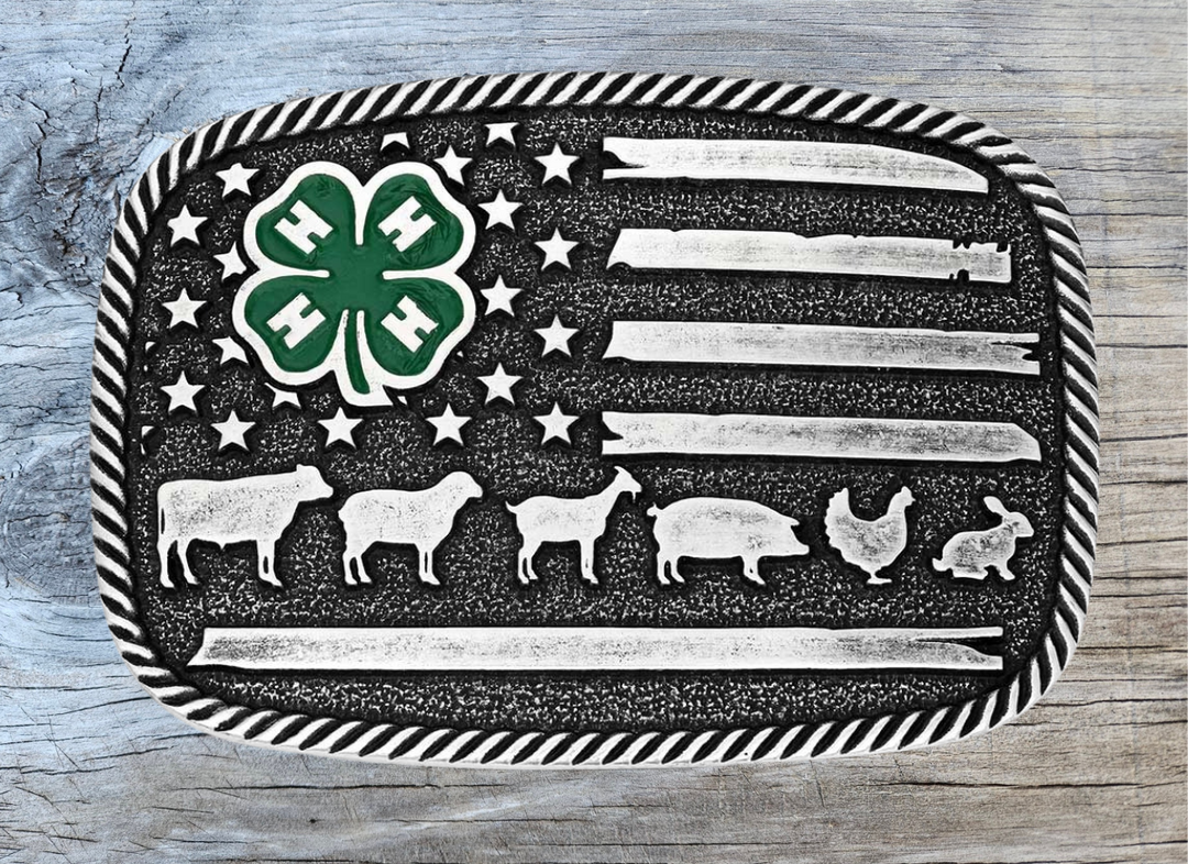 The 4-H Livestock Buckle features a silver toned, square shape with a twisted rope edge. An American flag background displays a green painted 4-H clover among the stars, and finishes with one of the stripes as a line of livestock. Fits 1 1/2" belts and is approx. 3" tall x 4"across. Available at&amp;nbsp;our shop just outside Nashville in Smyrna, TN. Made by Montana Silversmith.

Silver over a white metal alloy. Paint. Montana Armor to prevent tarnish.