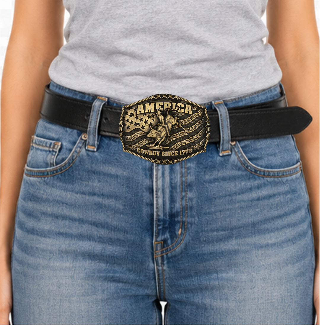 Stand for liberty and Western heritage for all with the Cowboy Since 1776 Attitude Buckle. The waving American flag provides the backdrop for the design. The word "America" sits above the bull rider figure. The words "Cowboy Since 1776" is beneath the bull rider figure. A roped border with barbed wire design creates the edge of the buckle, giving the piece a rustic look. Fits 1.5 inch belts. Find it online or at our shop just outside Nashville in Smyrna, TN.