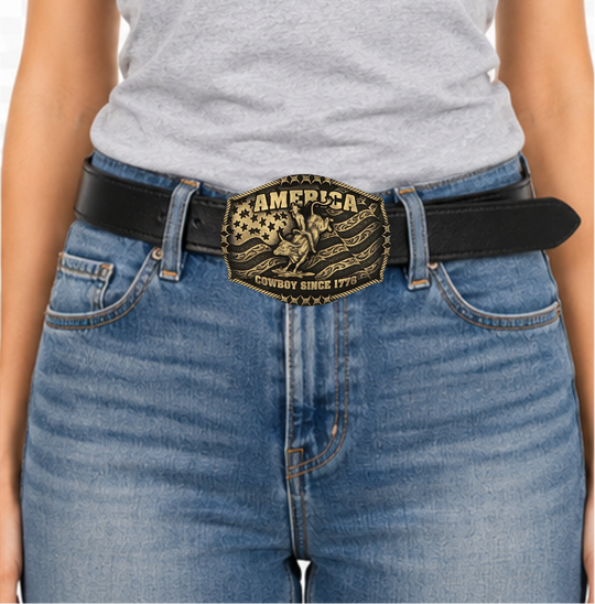 Stand for liberty and Western heritage for all with the Cowboy Since 1776 Attitude Buckle. The waving American flag provides the backdrop for the design. The word "America" sits above the bull rider figure. The words "Cowboy Since 1776" is beneath the bull rider figure. A roped border with barbed wire design creates the edge of the buckle, giving the piece a rustic look. Fits 1.5 inch belts. Find it online or at our shop just outside Nashville in Smyrna, TN.