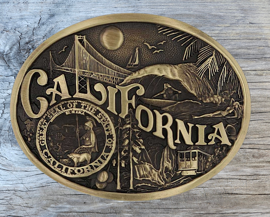 Celebrate California State with this buckle highlighting the sun, sailing, surfing, and sand, the Golden Gate Bridge, mountain trolley, and the great state seal! Brass plate over a solid cast metal alloy is antiqued and buffed to highlight the details.

Fits 1 1/2" belts and is approx. 3" tall x 4" across. Available at our shop just outside Nashville in Smyrna, TN. Made by Montana Silversmiths.
