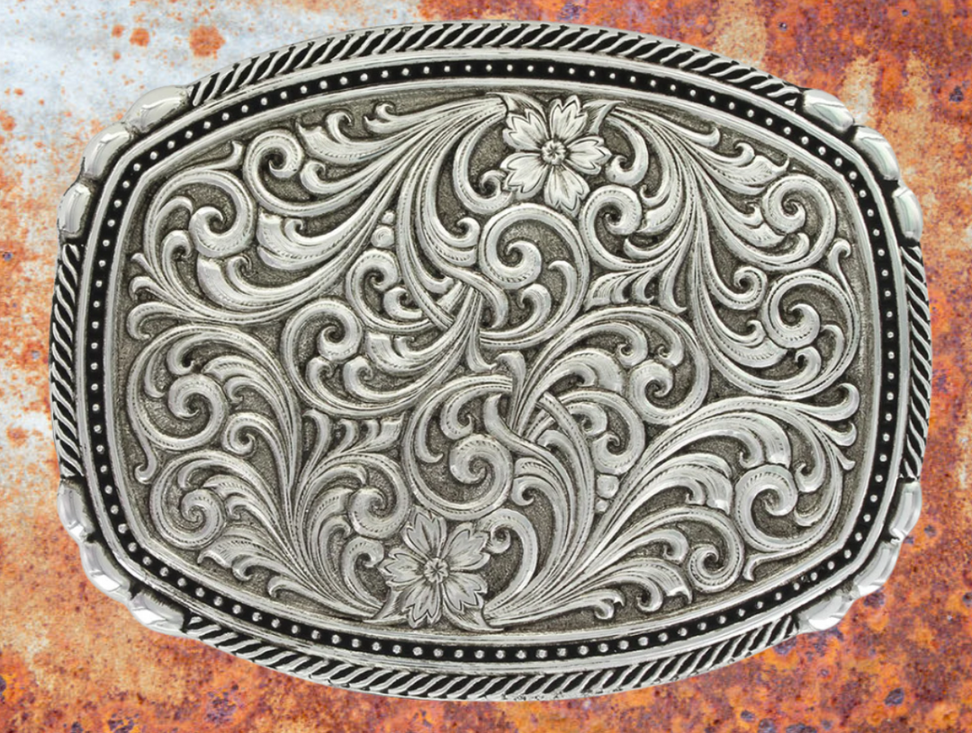This buckle features a beautiful Intricate Classic Western Scroll pattern as the main design. Its antiqued curved rectangular shape is accented with twisted silver finished rope edging and high-domed beads, framing the bright cut Western scroll design. It can fit a standard 1.5 inch belt and measures approximately 3 3/4"" across x 3" tall. You can find it at our Smyrna, TN location, just a short drive from downtown Nashville. Made by Montana Silversmith.