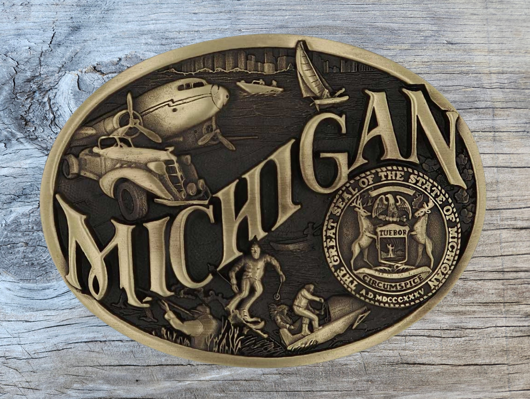 Celebrate Michigan State with this buckle highlighting modes of transportation, hunting, skiing and the state seal! Brass plate over a solid cast metal alloy is antiqued and buffed to highlight the details.

Fits 1 1/2" belts and is approx. 3" tall x 4" across. Available at our shop just outside Nashville in Smyrna, TN. Made by Montana Silversmiths.