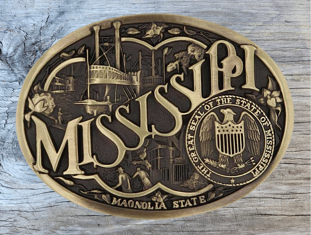 Celebrate Mississippi State with this buckle highlighting the Magnolia State heritage including steamboats and the great state seal. Brass plate over a solid cast metal alloy is antiqued and buffed to highlight the details.

Fits 1 1/2" belts and is approx. 3" tall x 4" across. Available at our shop just outside Nashville in Smyrna, TN. Made by Montana Silversmiths.