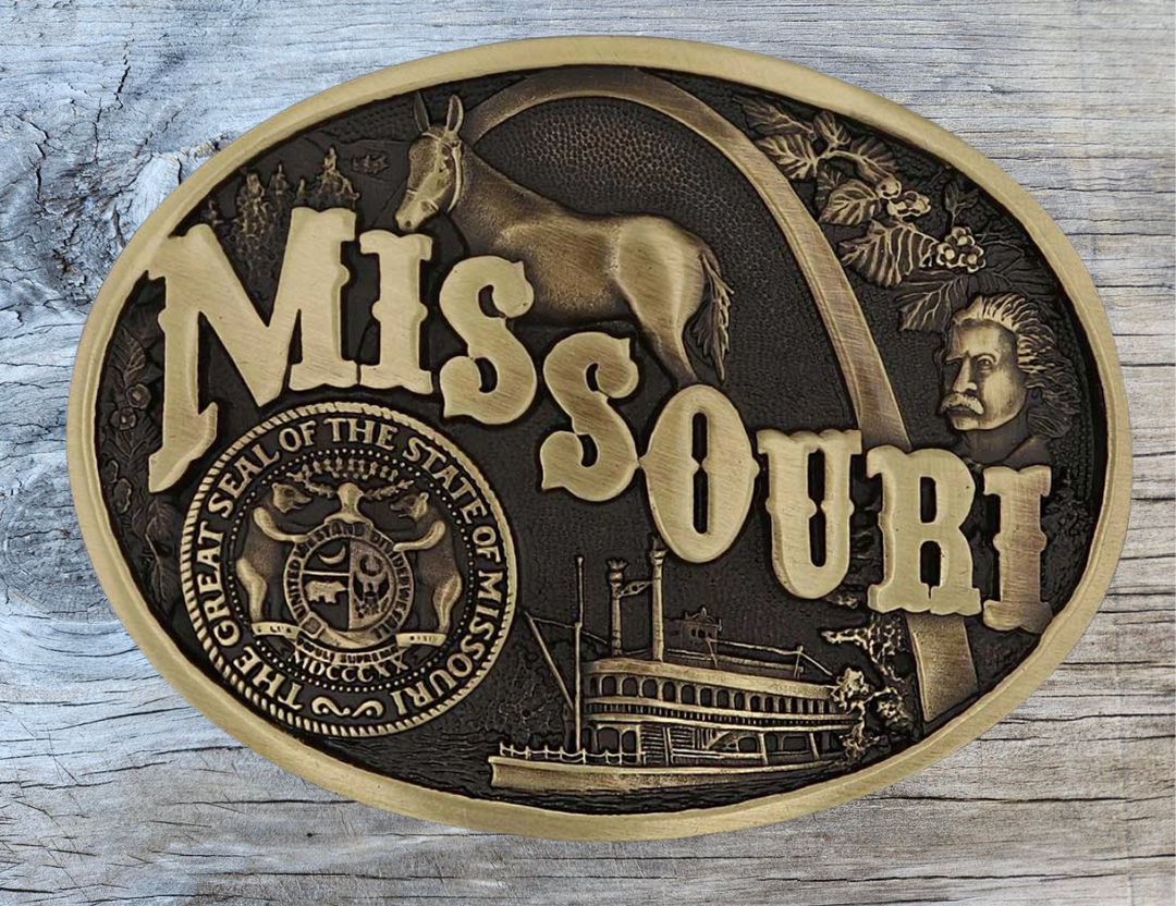 Celebrate Missouri State with this buckle highlighting the St. Louis Arch, Missouri River Steamboats, the Missouri Mule, Albert Einstein for his influence, and the great state seal! Brass plate over a solid cast metal alloy is antiqued and buffed to highlight the details.

Fits 1 1/2" belts and is approx. 3" tall x 4" across. Available at our shop just outside Nashville in Smyrna, TN. Made by Montana Silversmiths.