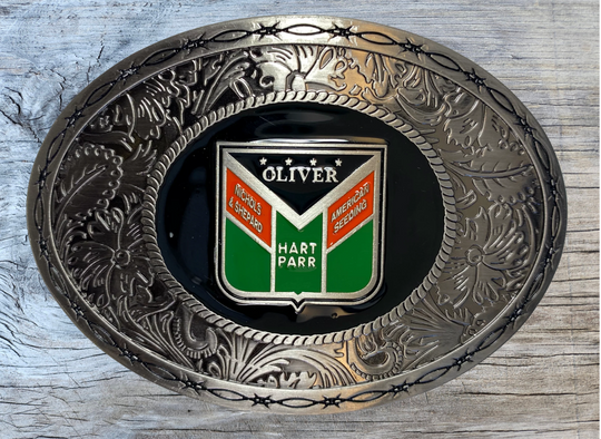 Western influenced oval buckle with barbed wire and western tooling and Oliver Tractor logo in the center. Available online and in our shop just outside Nashville in Smyrna, TN. Approx. 3"x4" in size.