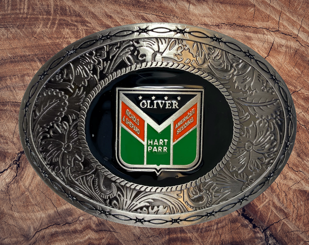 Western influenced oval buckle with barbed wire and western tooling and Oliver Tractor logo in the center. Available online and in our shop just outside Nashville in Smyrna, TN. Approx. 3"x4" in size.