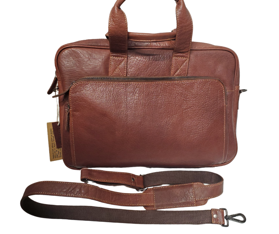 The Colonel Leather Laptop Bag is a no-frills bag that's perfect for the daily hustle. Crafted from buttery soft pebble grain leather, it only gets better with age. With a spacious main pocket, computer sleeve, and room for paperwork and snacks, it's got your weekday needs covered. Power cords? No problem! Just stash them in one of the two outside zippered pockets. And for ultimate convenience, it comes with an adjustable shoulder strap. Swing by our Smyrna, TN shop and snag one today!