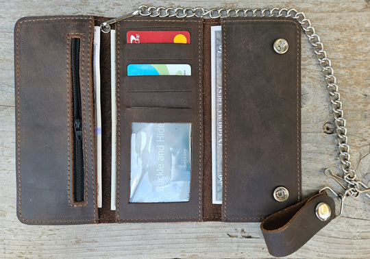 The Road Dog Tri-fold Biker Wallet is a lightweight leather thin profile chain wallet with a basic chrome plated chain that is detachable. Snap-button closure, 5 credit card slots, 1 clear ID window, 1 zippered coin pocket, 3 full-length storage pockets for cash, receipts, or additional cards. Offered in a black and brown. Closed Size: 7" L × 3.5" H. Available at our Smyrna, TN shop, near Nashville.