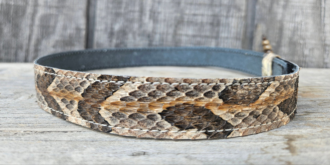 This Natural Copper Canyon Eastern Canebrake Rattlesnake Skin Hatband has a Rattle at the end of the band. It has more a Striped Copper pattern than a traditional Diamondback. Actual snakeskin with a pigskin backing and adjustment with a Velcro loop that you can tighten or loose to fit your favorite hats. You can bring your hat and try them out if you come to our Smyrna, TN shop not far from Nashville.

1" width