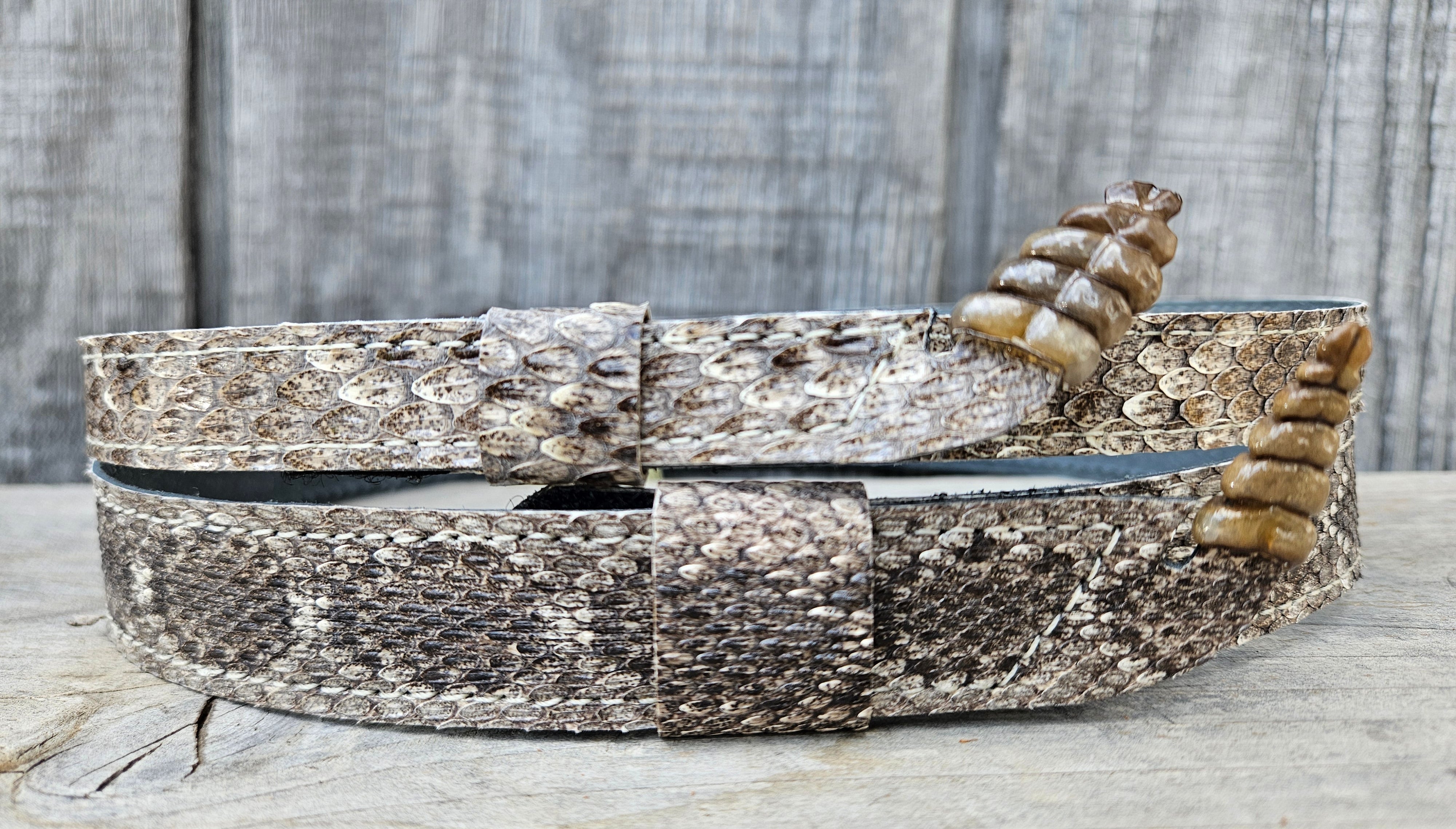 This is a Western Diamondback Snake Skin Hatband. The Western pattern is a little less defined than the Eastern or a Canebrake. An up-raised Rattle attached at the end of band will connect together with a hook & loop adjustment and a sliding keeper. Authentic Rattlesnake skin with a pigskin back. Of course you can pick them out if you come to our Smyrna, TN shop not far from Nashville.