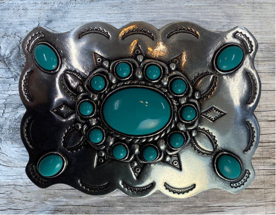 Southwestern style belt buckle with Southwestern tooling, scalloped design around edges, and simulated turquoise stones, approx. size 3 1/2" wide by 2 1/2" tall.  Color is antique silver, buckle is made of zinc. Fits belts 1 1/2" wide. Available online and in our shop just outside Nashville in Smyrna, TN. Back of buckle is pictured.