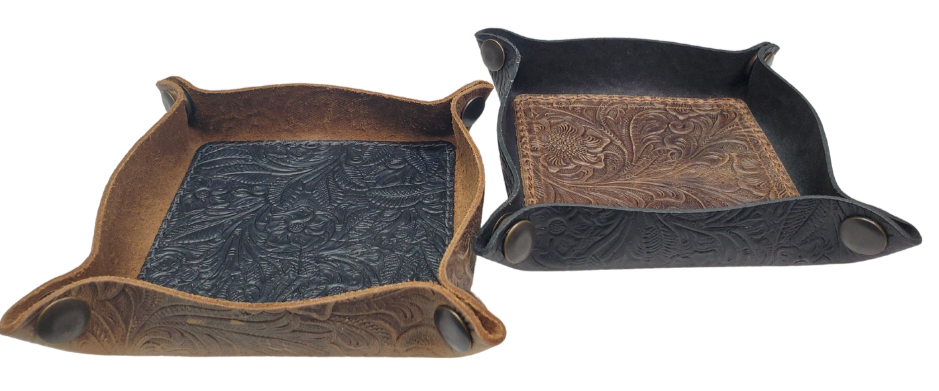 Our Western Leather Valet Tray, crafted in Smyrna, TN, easily folds flat by unsnapping its four Antique Brass snaps—perfect for travel. Its handy 4" x 4" size keeps your everyday essentials like keys and wallet organized. Featuring a classic embossed floral design, it pairs effortlessly with any style. Pick your favorite from four Black and Brown combos! Colors my vary.