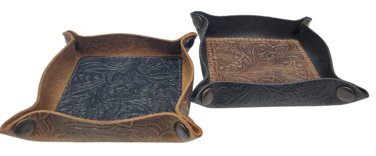 Our Western Leather Valet Tray, crafted in Smyrna, TN, easily folds flat by unsnapping its four Antique Brass snaps—perfect for travel. Its handy 4" x 4" size keeps your everyday essentials like keys and wallet organized. Featuring a classic embossed floral design, it pairs effortlessly with any style. Pick your favorite from four Black and Brown combos! Colors my vary.