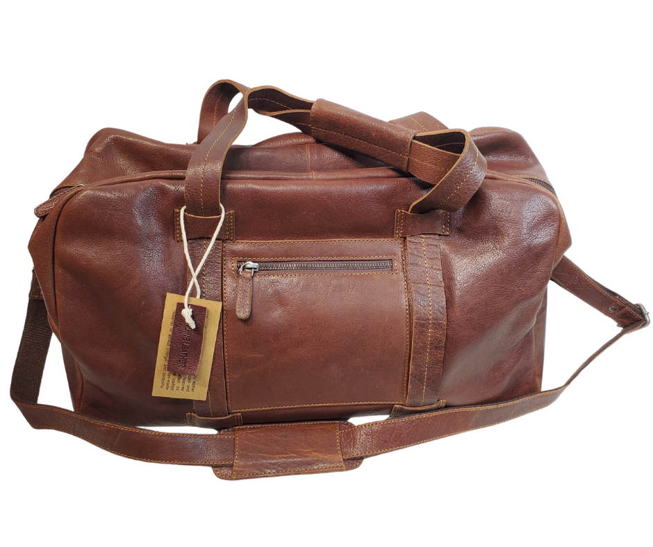 The Traveler Leather Duffel bag is available at our Smyrna, TN shop not far from Nashville. It has a single zip pocket on the side approx. 6.5 x 6.5”. Detachable leather shoulder strap is reinforced with cotton webbing, 2 leather strap handles, one on each side with reinforcement stitching and handle snaps. Spacious inside compartment with a two-way zipper. Inside pockets on each side one zips and the other is open. Lined with sturdy fabric. Bottom of bag has five rounded feet 