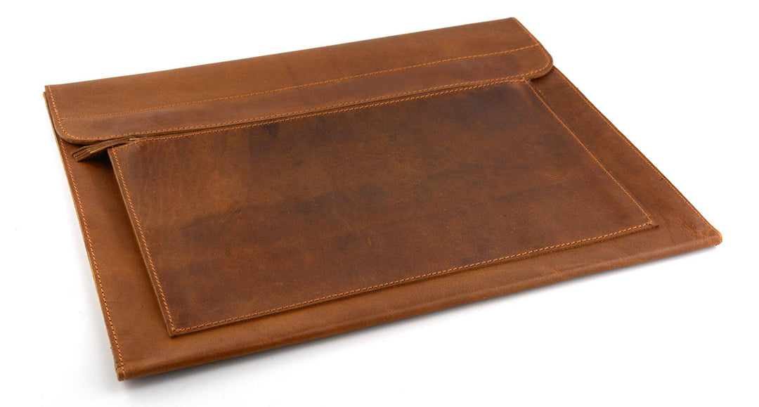 The Analyst is a tablet or thin laptop sleeve handmade from full-grain leather. A practical gift idea for yourself, family, or friends. Offered in a 13" or a 15". Side gussets extend approximately 3/4 inches on each side for both the main pocket and the accessory pocket. Distressed brown leather with antique brass magnet closures and zipper. Part of our Home Office items now at our Smyrna, TN shop.