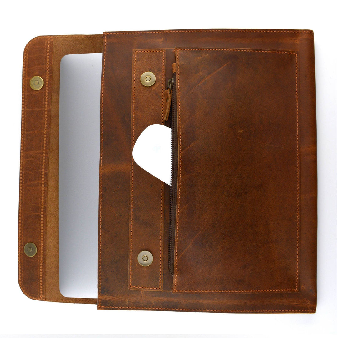 The Analyst is a tablet or thin laptop sleeve handmade from full-grain leather. A practical gift idea for yourself, family, or friends. Offered in a 13" or a 15". Side gussets extend approximately 3/4 inches on each side for both the main pocket and the accessory pocket. Distressed brown leather with antique brass magnet closures and zipper. Part of our Home Office items now at our Smyrna, TN shop.