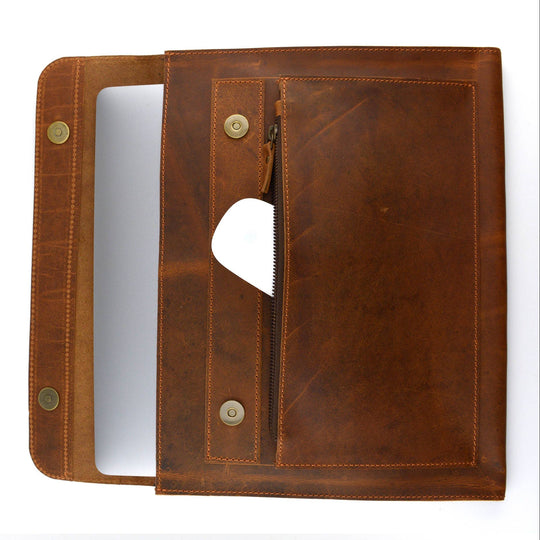 The Analyst is a tablet or thin laptop sleeve handmade from full-grain leather. A practical gift idea for yourself, family, or friends. Offered in a 13" or a 15". Side gussets extend approximately 3/4 inches on each side for both the main pocket and the accessory pocket. Distressed brown leather with antique brass magnet closures and zipper. Part of our Home Office items now at our Smyrna, TN shop.